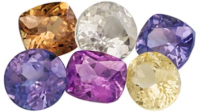 A group of faceted and different colored sapphire gemstones.
