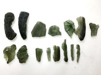 These are multiple uncut moldavite specimens.