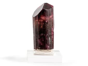 Natural unfaceted dark pink rubellite specimen on a small stand.