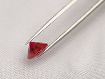 diamond cut ruby held by tweezers
