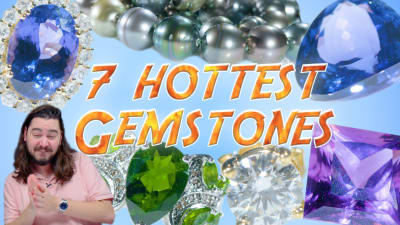 A gemologist admires seven beautiful and colorful gemstones.