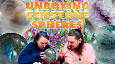 Two gemologists peer into a gemstone sphere.